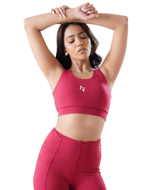 Woman wearing a red sports bra and leggings with a logo on a white background