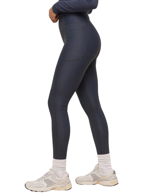 Person wearing dark gray leggings and white sneakers on a white background