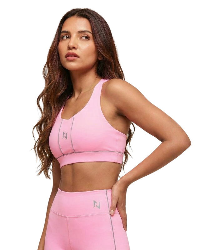 Woman wearing a pink sports bra and leggings with a visible brand logo on a white background
