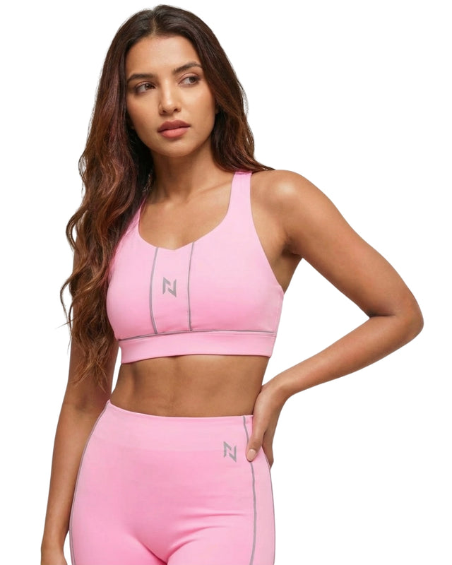 Woman wearing a pink sports bra and leggings with a visible brand logo on a white background