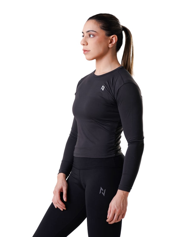 Woman wearing a black long-sleeve athletic top and leggings on a white background