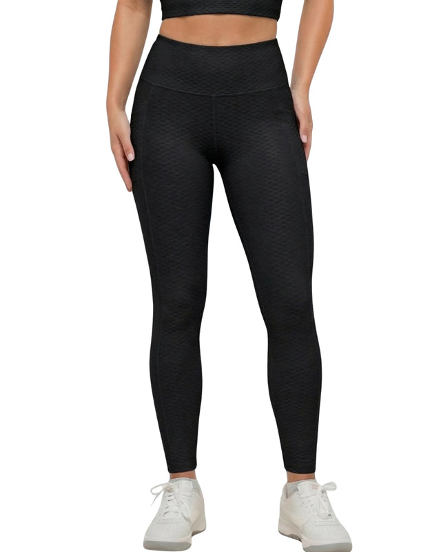 Person wearing black textured leggings on a white background