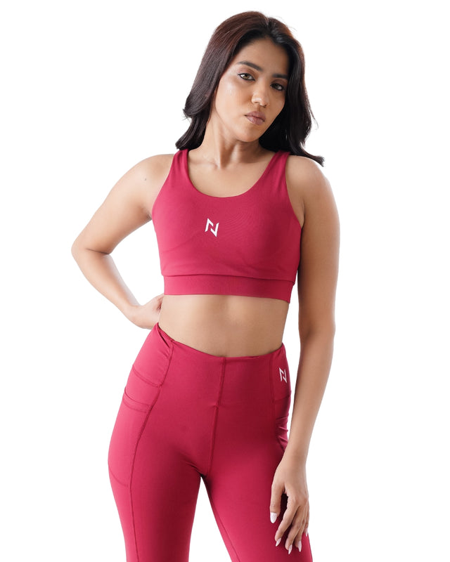 Woman wearing a red sports bra and leggings with a logo on a white background