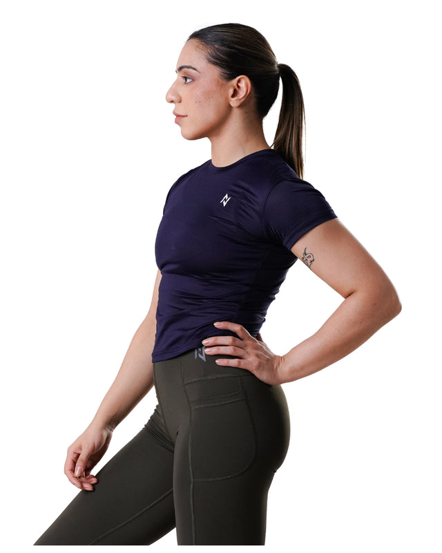 Woman wearing a dark blue athletic shirt and black leggings on a white background
