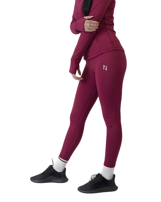 Person wearing a maroon tracksuit with a logo on a white background