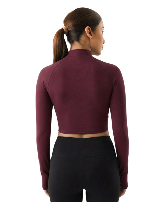 Woman wearing a maroon long-sleeve athletic top on a white background