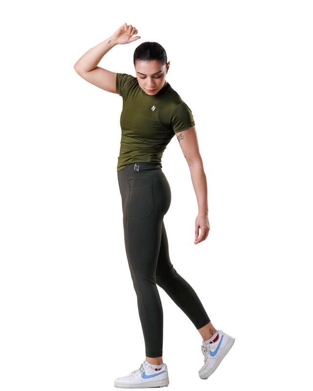 Woman wearing green athletic top and black leggings on a white background