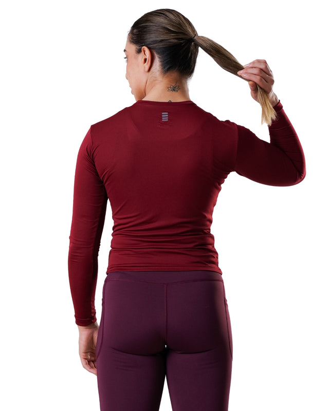Person wearing a maroon long-sleeve athletic top and leggings on a white background
