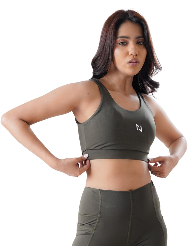 Woman wearing a green sports bra and leggings with a white logo on a white background