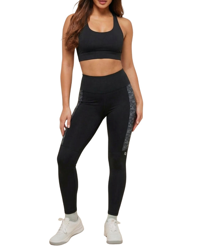 Person wearing a black sports bra and leggings set on a white background