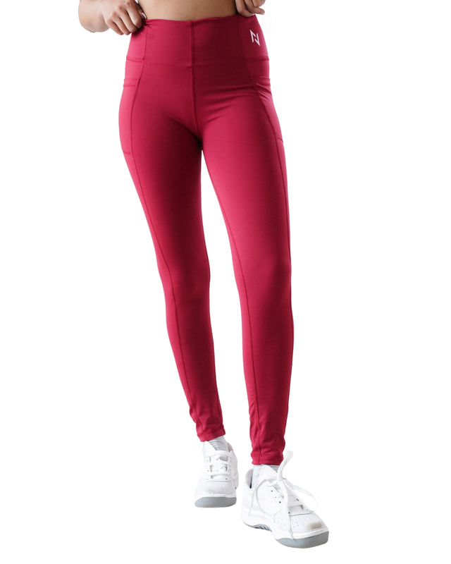 Red leggings with a brand logo worn by a person on a white background