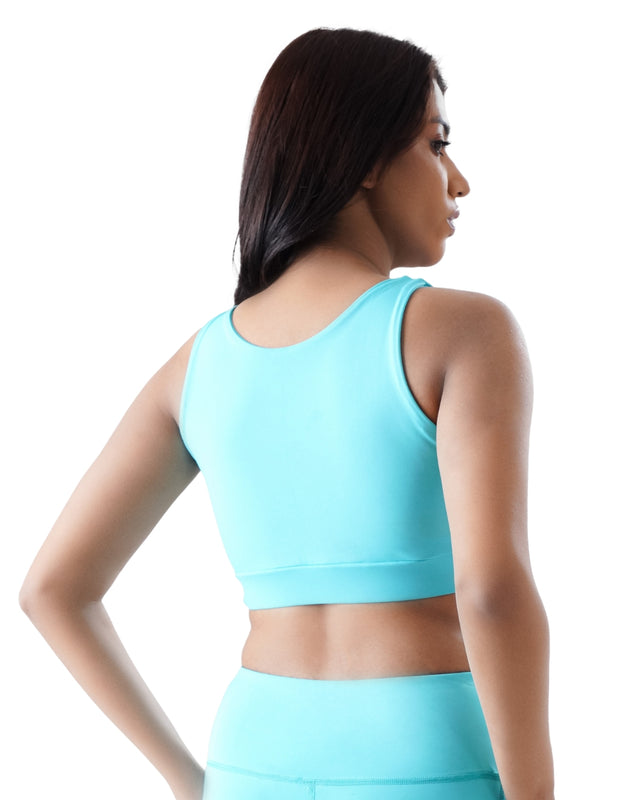 Woman wearing a light blue sports bra and leggings on a white background