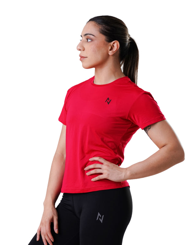 Woman wearing a red athletic shirt and black pants with a brand logo on a white background