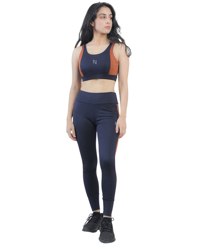 Woman wearing a navy sports bra and leggings set on a white background