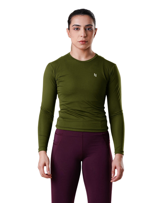 Woman wearing a green long-sleeve athletic shirt and purple leggings on a white background