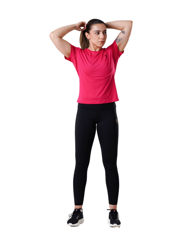 Woman wearing a pink athletic shirt and black leggings on a white background