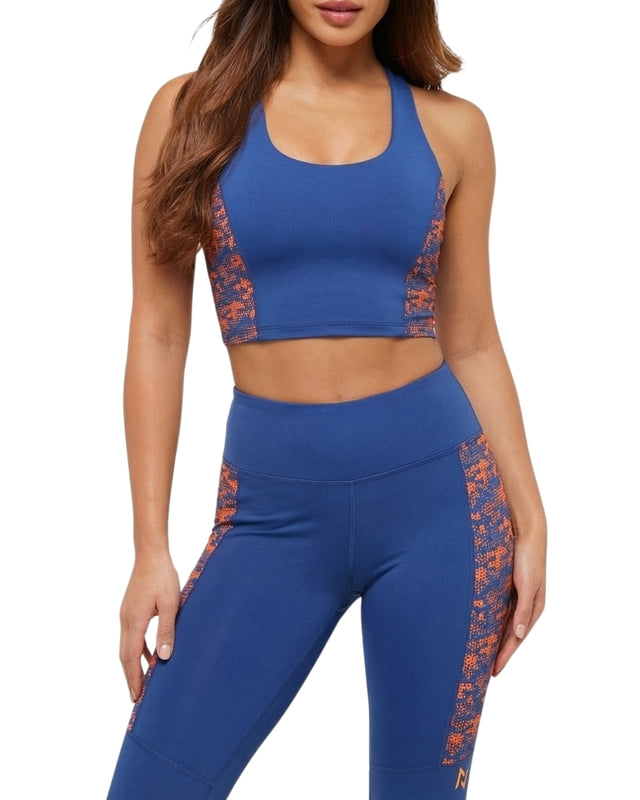 Woman wearing a blue sports bra and leggings with orange accents on a white background