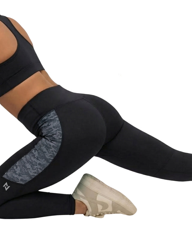 Person wearing black leggings with gray pattern and white sneakers on a white background