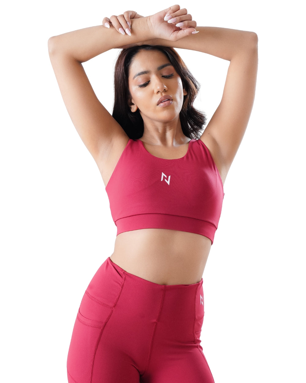 Woman wearing a red sports bra and leggings with a logo on a white background