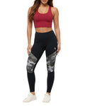 Woman wearing black leggings with camouflage patterns and a red sports bra on a white background