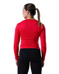 Person wearing a red long-sleeve athletic top and black leggings on a white background