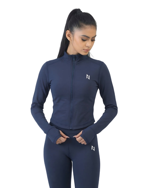 Woman wearing a navy blue athletic jacket and leggings with a logo on a white background