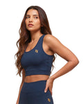 Woman wearing a navy blue sports bra and leggings with a logo on a white background