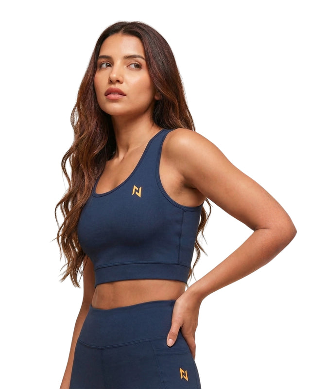 Woman wearing a navy blue sports bra and leggings with a logo on a white background