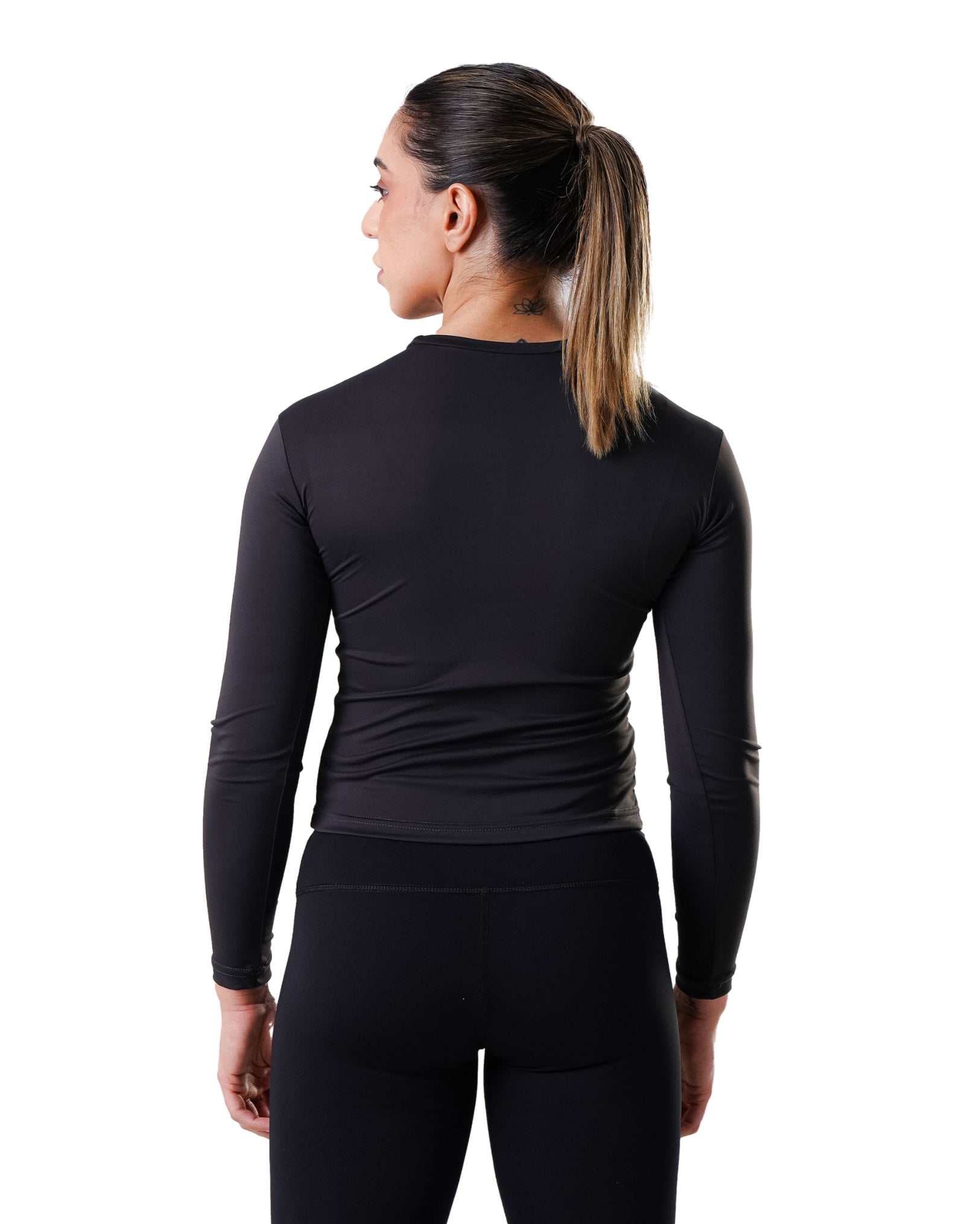 Person wearing a black long-sleeve athletic top and leggings on a white background