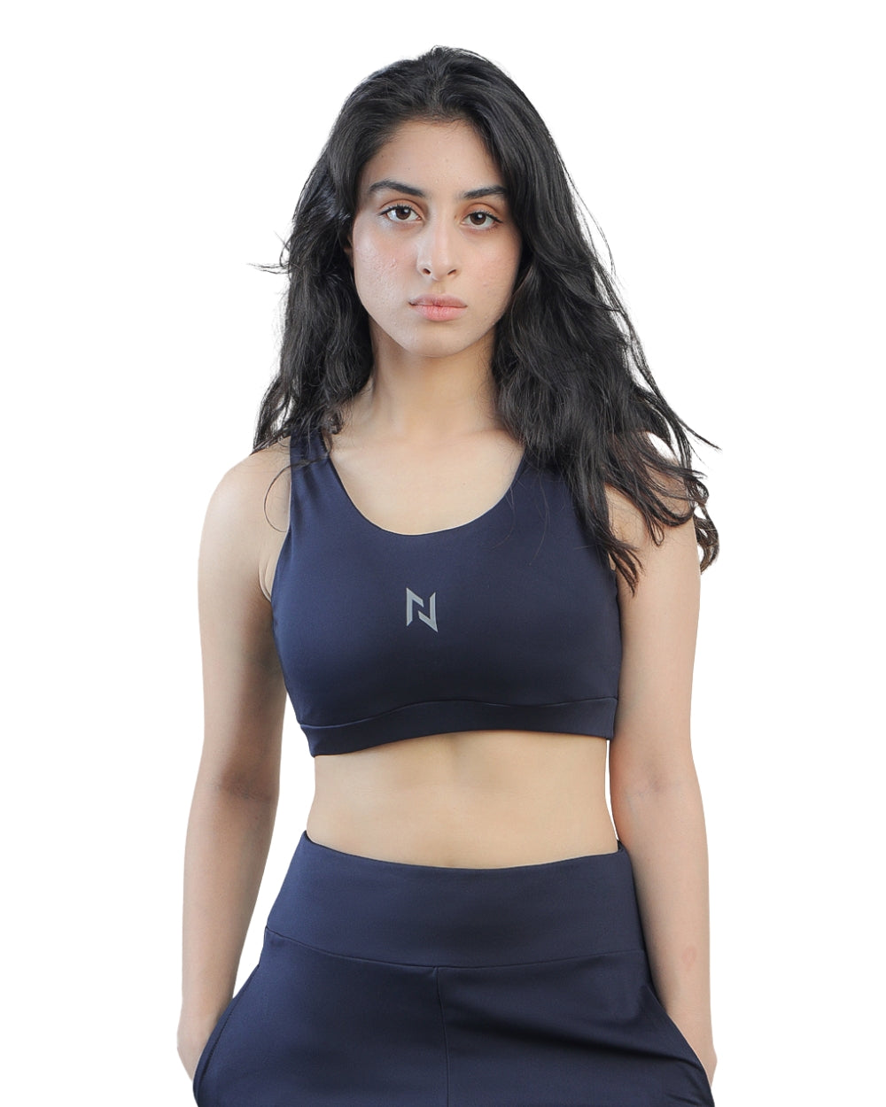 Woman wearing a navy blue sports bra and leggings with a logo on a white background