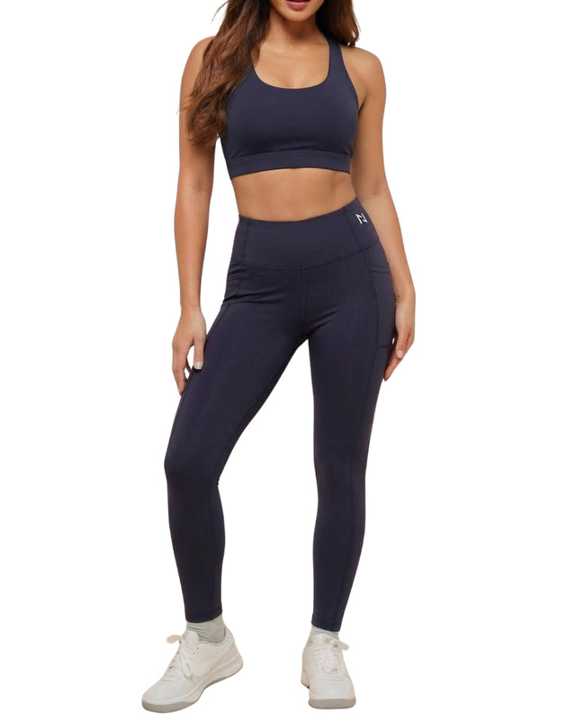 Person wearing navy athletic bra and leggings set on a white background