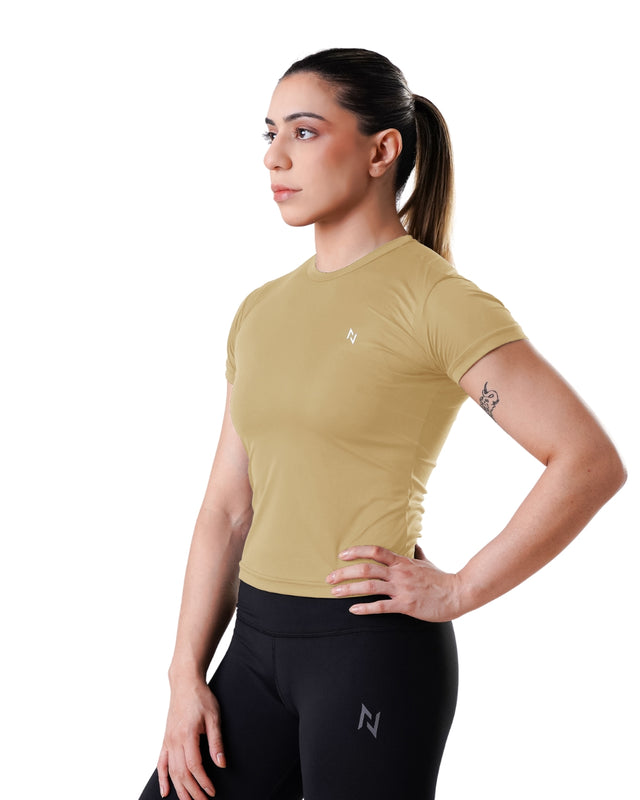 Woman wearing a beige athletic shirt and black leggings with a logo on a white background