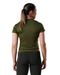 Woman wearing a green athletic shirt and black leggings on a white background