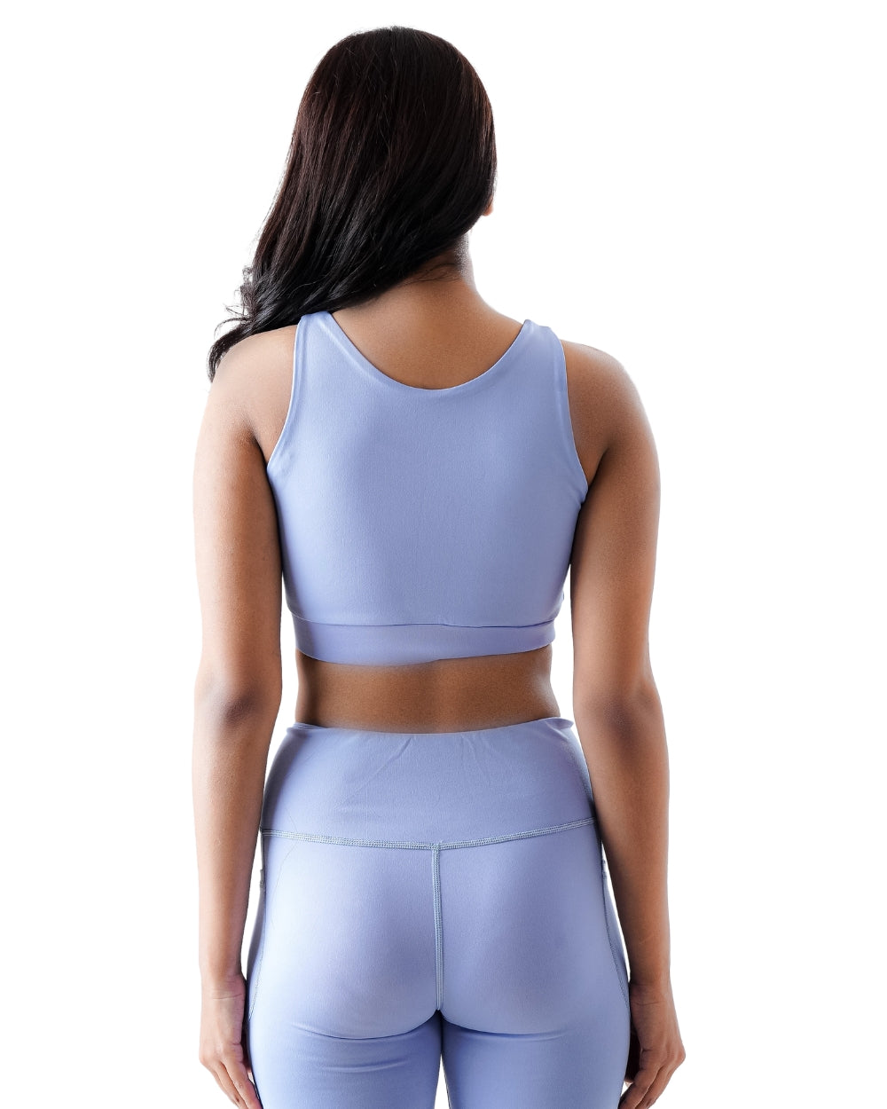 Woman wearing a light purple sports bra and leggings on a white background