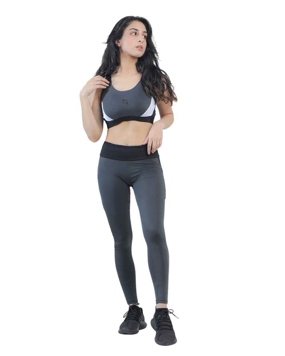 Woman wearing a gray sports bra and leggings on a white background