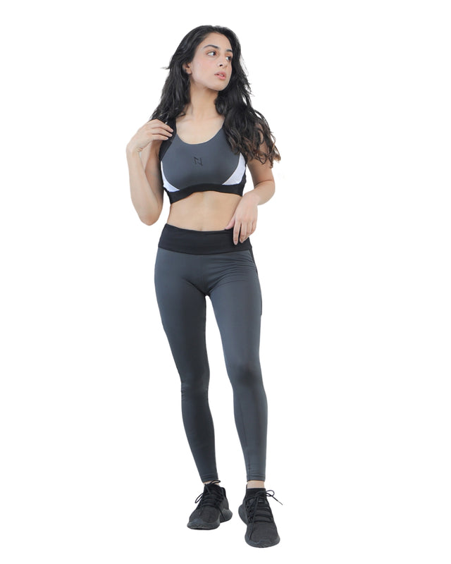 Woman wearing a gray sports bra and leggings on a white background