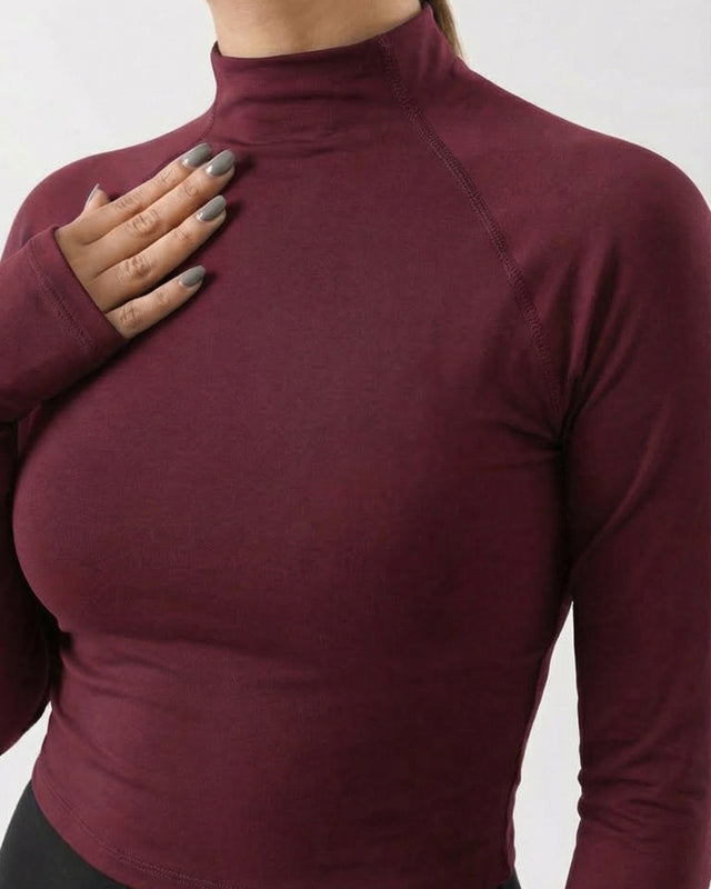 Maroon long-sleeve top worn by a person on a white background