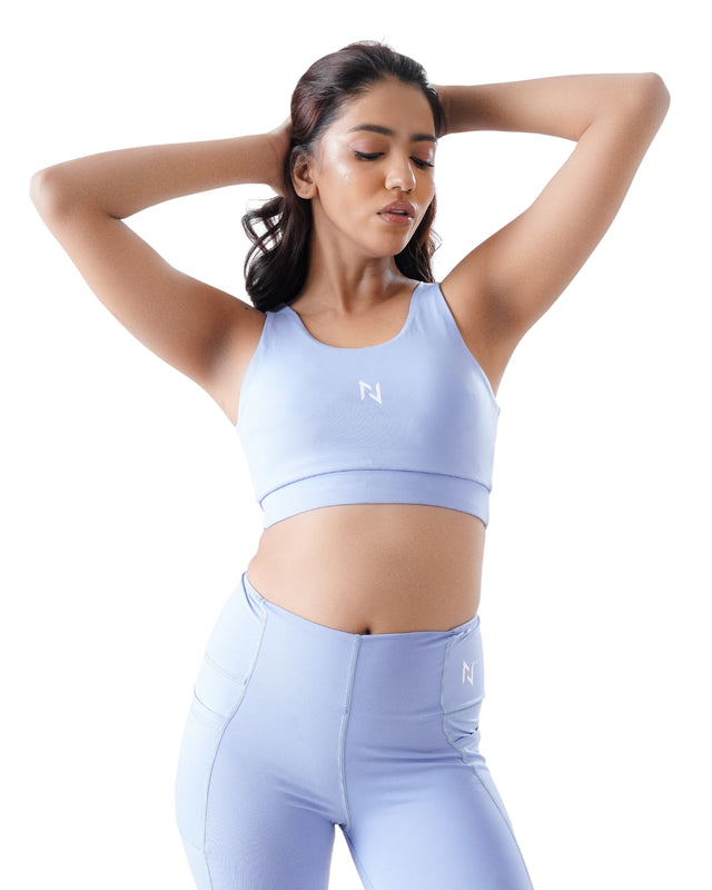 Woman wearing a light blue sports bra and leggings on a white background