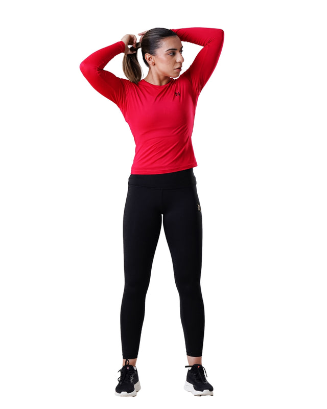 Woman wearing a red long-sleeve top and black leggings on a white background