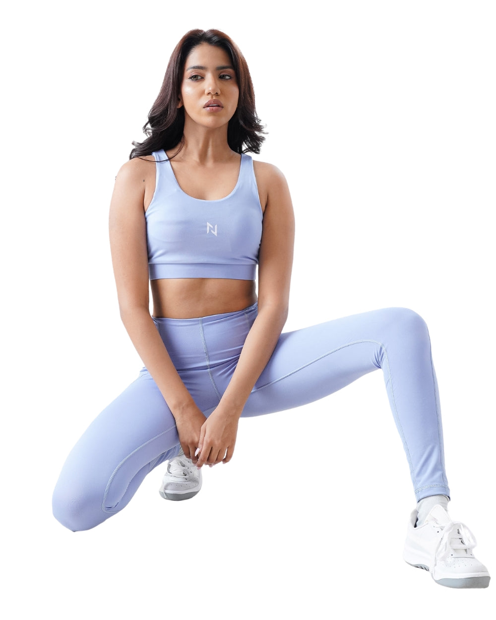 Woman wearing a light blue athletic outfit with a logo on a white background