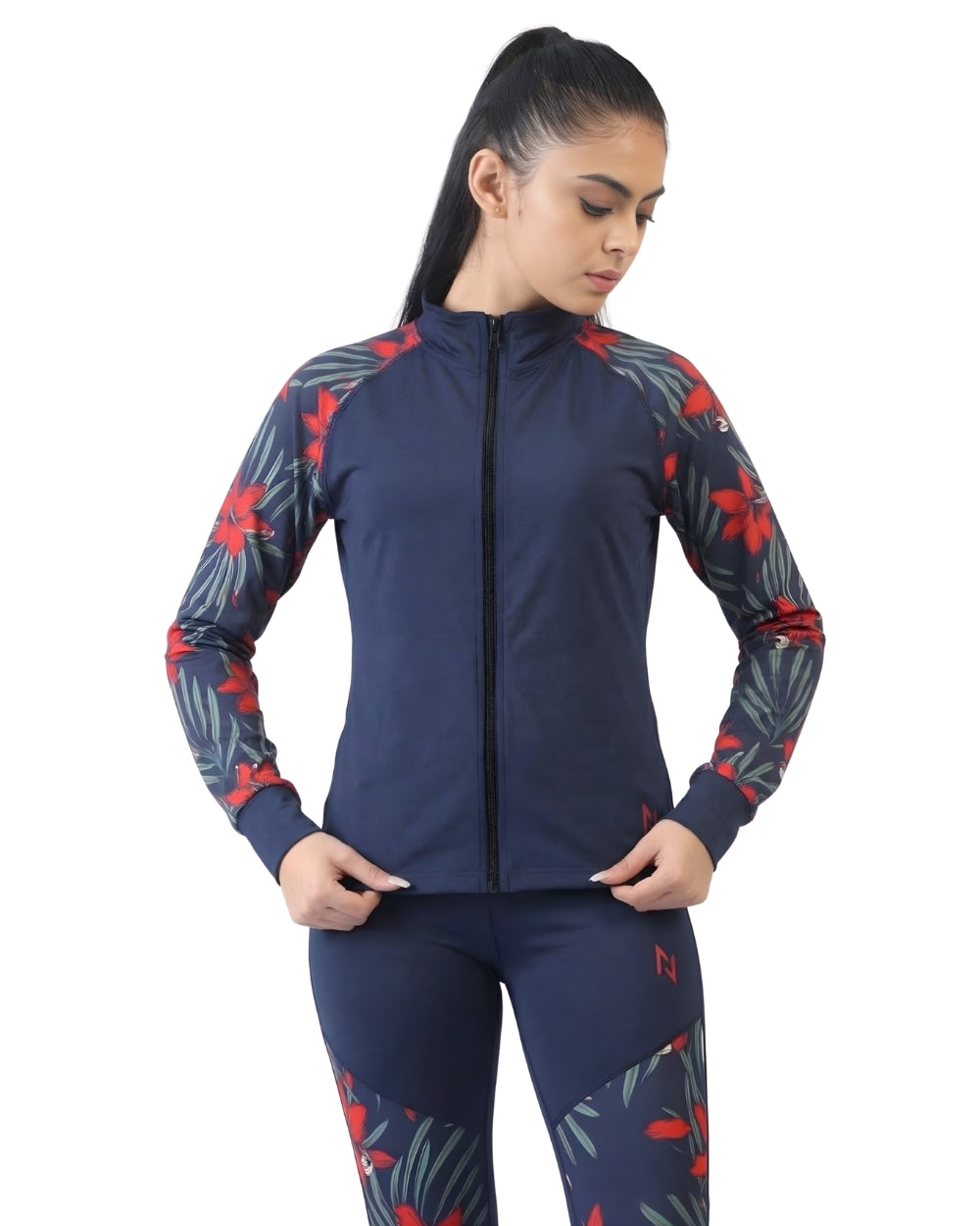 Woman wearing a navy blue athletic jacket and leggings with red and gray floral patterns on a white background
