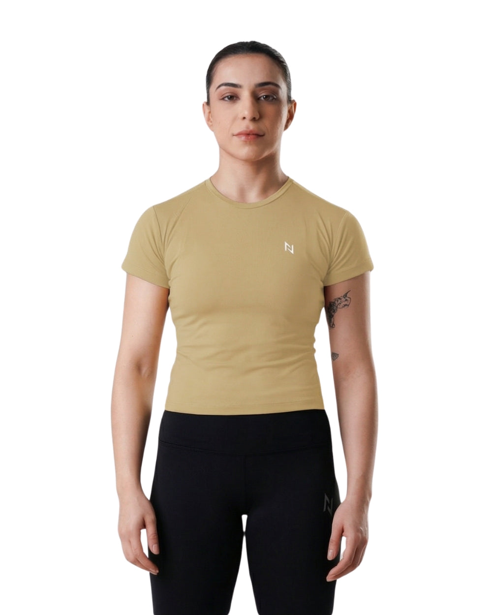 Woman wearing a beige athletic shirt and black leggings on a white background
