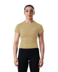 Woman wearing a beige athletic shirt and black leggings on a white background