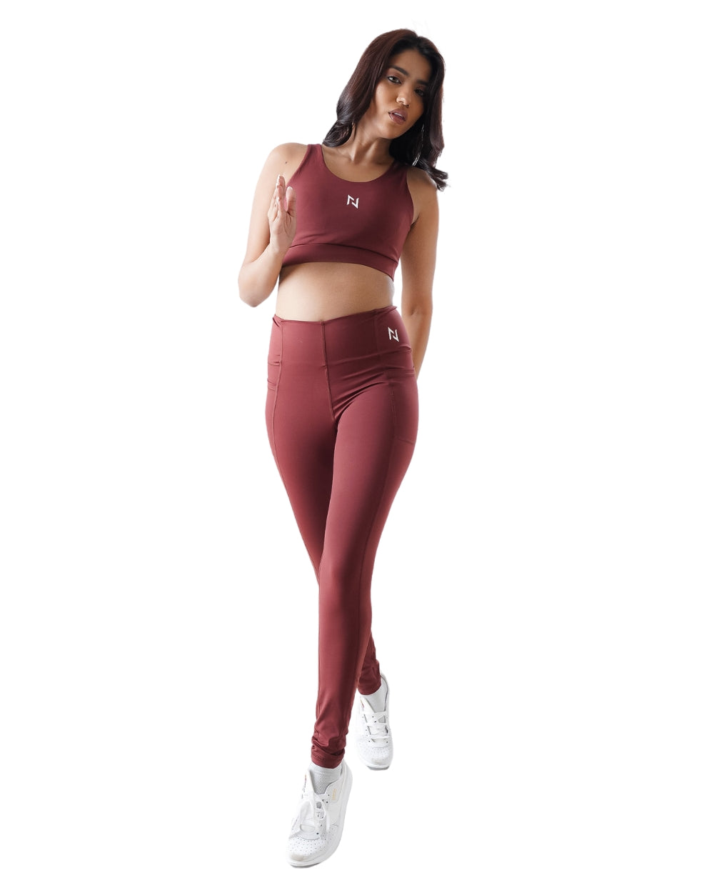 Woman wearing a maroon athletic outfit with a logo on a white background