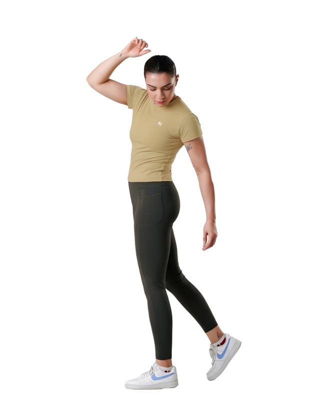 Woman wearing a beige t-shirt and black leggings on a white background