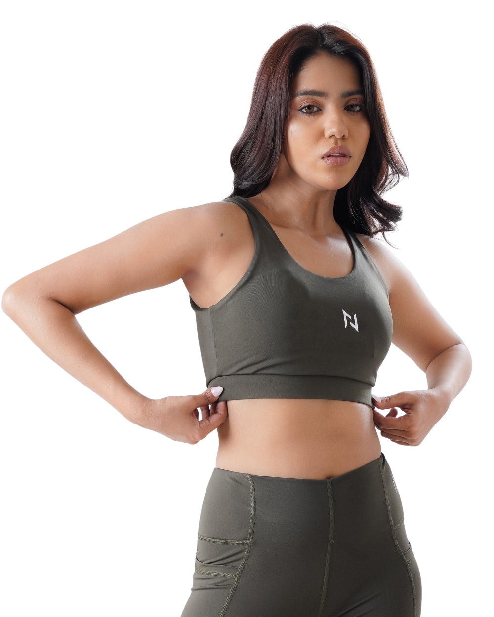 Woman wearing a green sports bra and leggings with a white logo on a white background