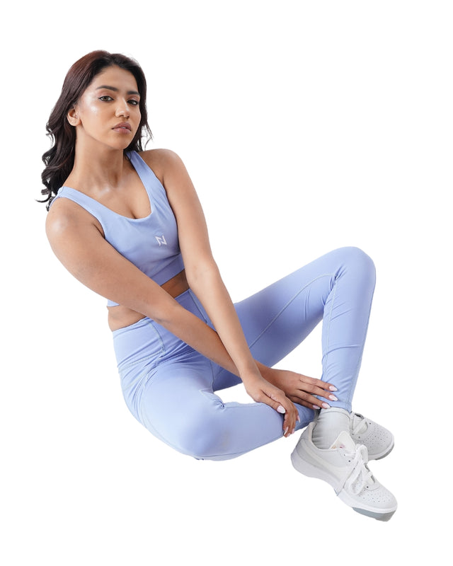 Woman wearing a light blue athletic outfit sitting on a white background