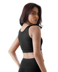 Woman wearing a black sports bra and leggings on a white background