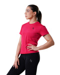 Woman wearing a pink athletic shirt and black leggings with a logo on a white background