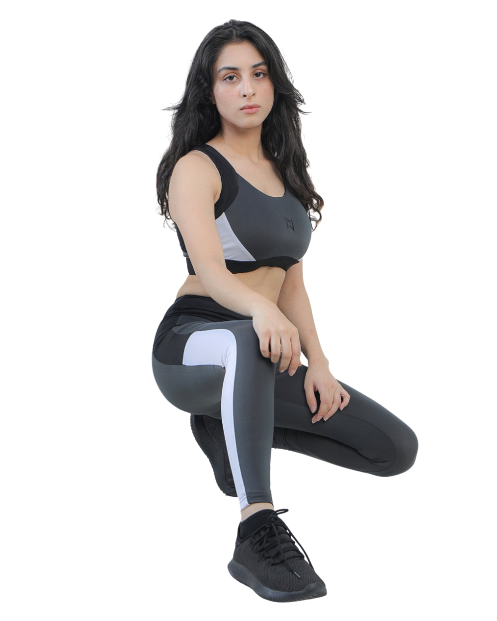 Woman wearing a black sports bra and leggings with white stripes on a white background